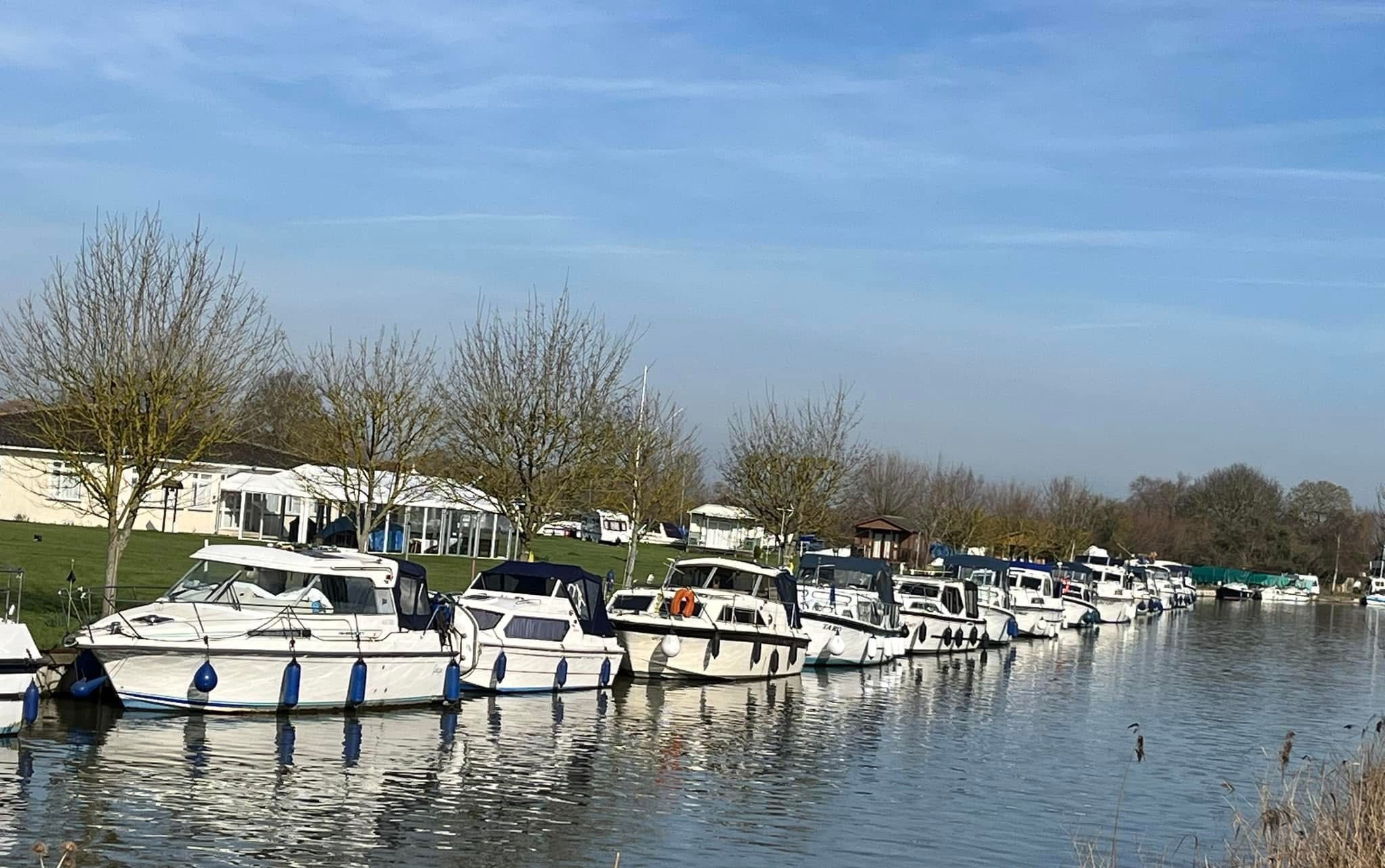 Motor cruisers moored along the Cambridge Motor Boat Club bank on the River Cam at Waterbeach